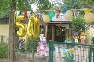 Eine goldene 50 aus Luftballons, Wimpelketten, im Hintergrund Kinder