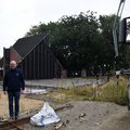 Eine Frau und ein Mann stehen links, rechts ein Teil eines roten LKW. Mittig eine Baustelle.