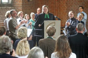 Viele Menschen applaudieren einer Frau stehend