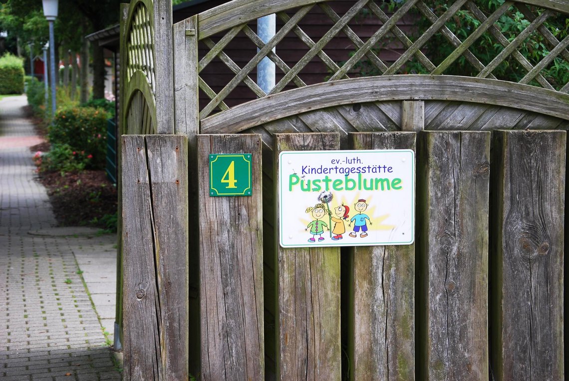 Logo der Kita auf verwittertem Holzzaun